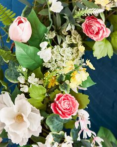 a bunch of flowers that are sitting on a table in front of a blue wall