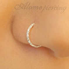 a close up view of the side of a woman's breast with a crescent shaped nose ring