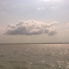 the sky is very cloudy over the water and there are some clouds in the distance