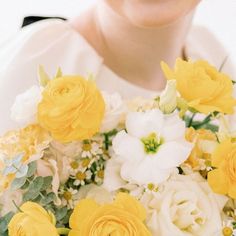 a woman holding a bouquet of yellow and white flowers