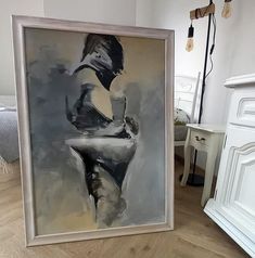 a painting on the floor next to a white dresser