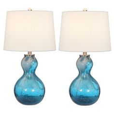 two blue glass vases with white lamps on top of each one in front of a white background