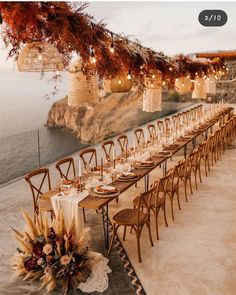 a long table is set up for an outdoor dinner with lights strung from the ceiling