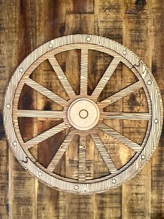 an old wooden wheel on the side of a wood wall with no people around it