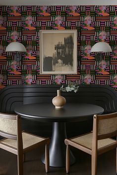 a black table with two chairs and a vase on it