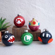 four ornaments with different designs on them sitting next to a potted plant in front of a white wall