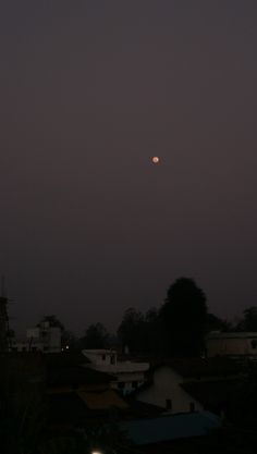 the moon is setting over some houses