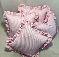 four pink pillows with ruffled edges on a white background