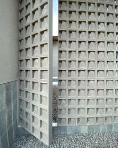 two concrete blocks are next to each other in front of a building with rocks and gravel on the ground