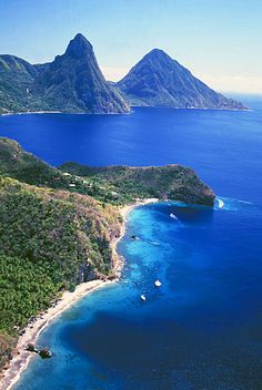 an aerial view of the ocean and two mountains in the distance with boats on the water