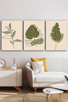 three green leaves are hanging on the wall above a white couch in a living room