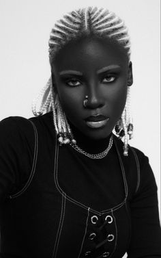 a woman with dreadlocks and piercing on her nose is posing for the camera