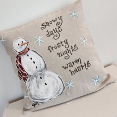 a snowman pillow sitting on top of a white table next to a wall with words written on it