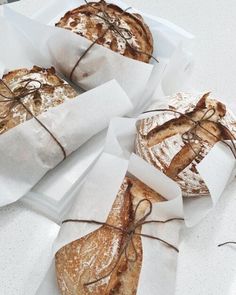 four pastries wrapped in brown paper sitting on top of a white countertop next to each other