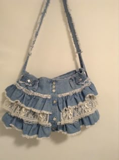 a blue jean skirt purse hanging on a wall with lace trimmings and buttons