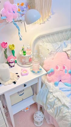 a white bed with pink and blue decorations on it's headboard next to a small table