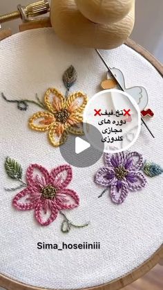 the embroidery is being worked on by someone using scissors and yarns to make flowers