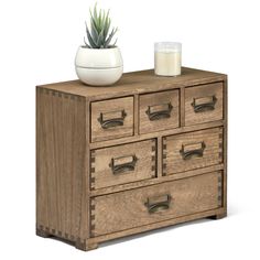 a wooden dresser with drawers and a plant on top, next to a candle holder