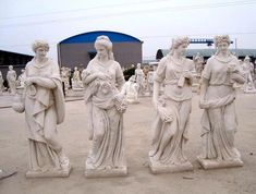 four statues of women holding flowers in their hands and standing next to each other on the ground