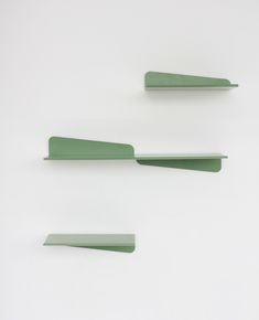 three green shelfs sitting next to each other on top of a white wall,