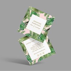 two business cards with tropical leaves on them, one in pink and the other in green