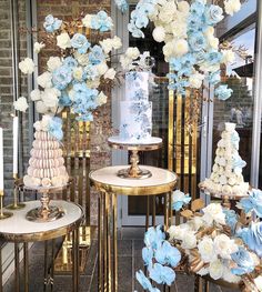 blue and white flowers are on display in front of a storefront with gold pedestals