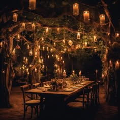 an outdoor dining area with candles lit up in the trees and lanterns hanging from the ceiling