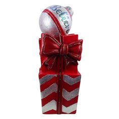 a red and silver gift box with two balls on top, tied in a bow