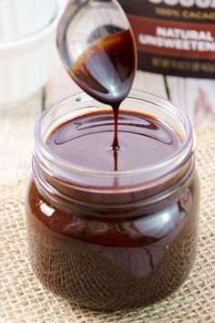 a jar filled with chocolate sauce sitting on top of a burlied table cloth