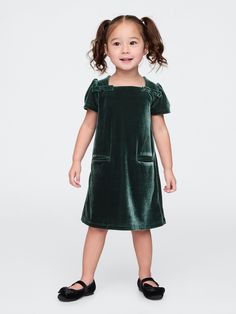 Soft, stretch velour dress.  Square neck with back button closures.  Short puff sleeves.  Bow details at front.  Front welt pockets.  This dress is made with 95% recycled polyester.  Compared to virgin materials, using recycled materials helps to reduce resource use and waste.  Shift silhouette with an easy fit.  Hits at the knee.  Sizes range from baby to toddler. Kids Holiday Dress, Christmas Card Outfits, Dress With Shoes, Essex Green, Toddler Holiday Dress, Black Toddler, Trendy Christmas Outfits, Dress Square Neck, Toddler Dresses