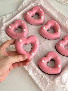 pink donuts with white pearls in the shape of heart shaped doughnuts on wax paper