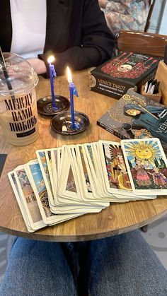 a person sitting at a table with cards and candles in front of them on the table