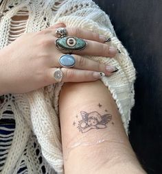 two hands holding each other with tattoos on their arm and wrist, one has an eyeball in the middle