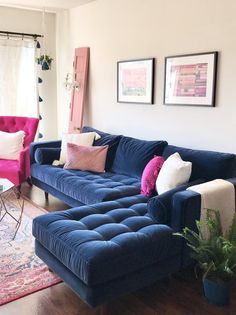 a living room with blue couches and pink chairs