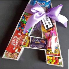 the letter shaped candy box is filled with candies and chocolates as well as a purple bow