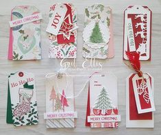 six christmas tags hanging from strings on a white surface