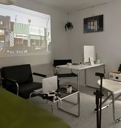 a room with two chairs, a desk and a projector screen