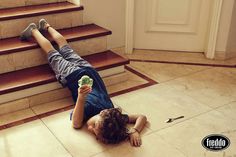 a young boy laying on the ground next to some stairs