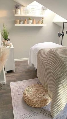 a white bed sitting under a window next to a rug on top of a wooden floor