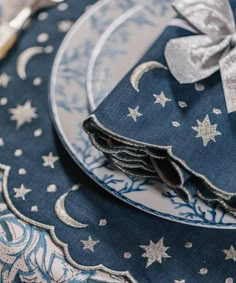 a blue and white place setting with silver stars on the napkins, fork and knife