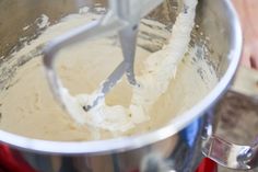 a mixing bowl filled with white batter and a metal beater on top of it