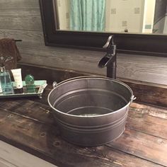 a large metal tub sitting on top of a wooden counter next to a mirror and soap dispenser