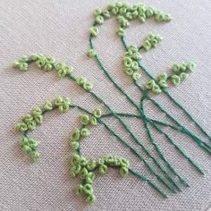 several green crocheted flowers sitting on top of a piece of cloth