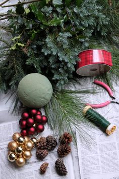 christmas decorations on top of a newspaper next to pine cones and other holiday decor items