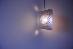 a light fixture hanging from the ceiling in front of a wall with shadows on it