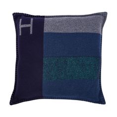 a blue and grey pillow with the letter h on it