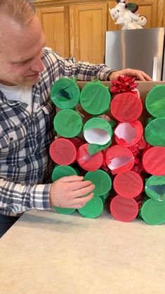 a man is making a christmas wreath out of toilet paper rolls