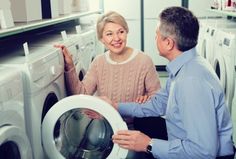 a man and woman looking at each other in front of washing machines