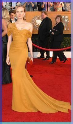 a woman in a yellow dress on the red carpet at an awards event with people around her