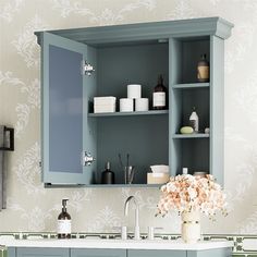 a bathroom with blue cabinets and floral wallpaper